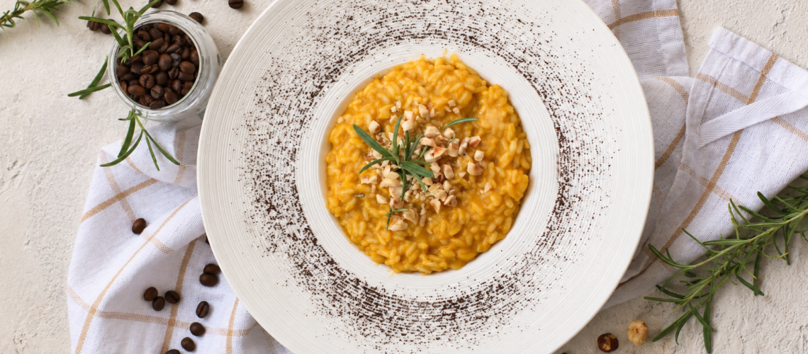 Risotto alla zucca, caffè e nocciole con crema di zucca, nocciole tostate e una leggera spolverata di caffè macinato.