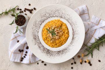 Risotto alla zucca, caffè e nocciole con crema di zucca, nocciole tostate e una leggera spolverata di caffè macinato.